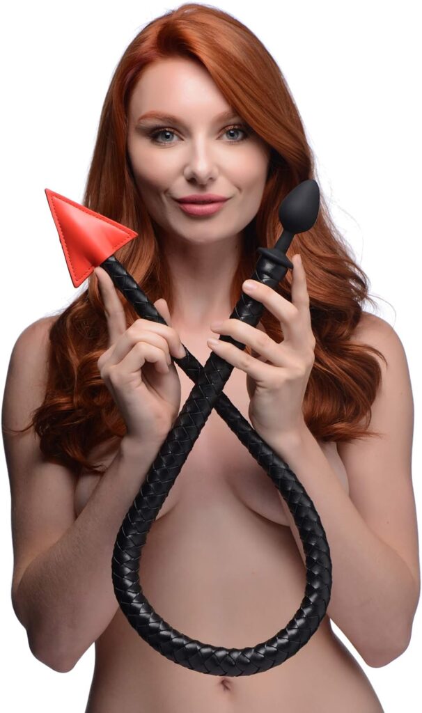Naked redhead woman holding a devil tail butt plug.